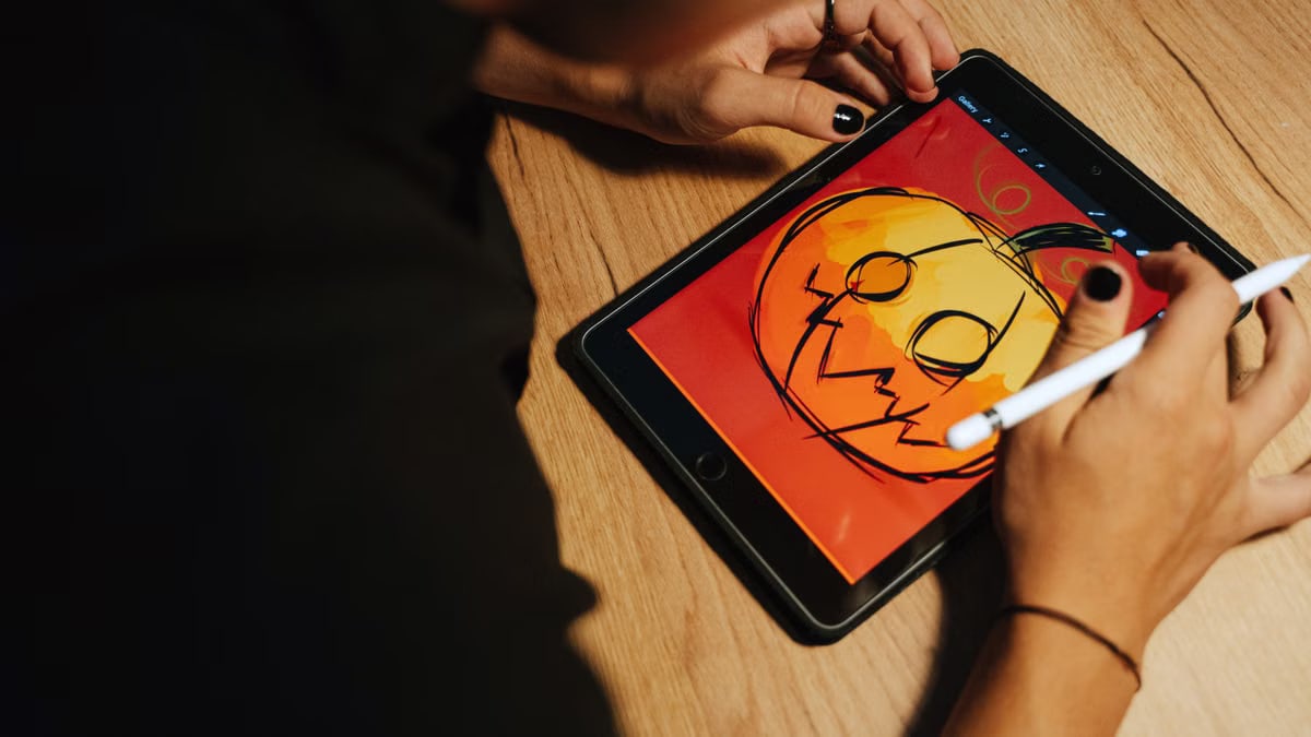 Creating a Halloween pumpkin illustration on a tablet with a stylus.
